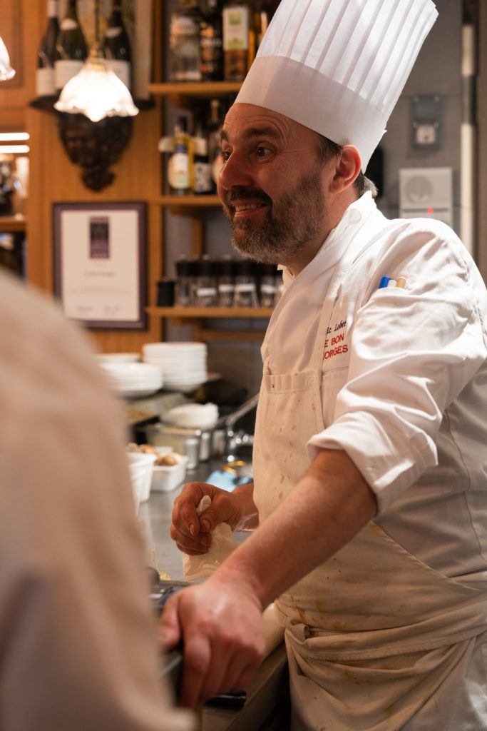 Le Chef tout sourire en train de parler et rire avec les clients du comptoir